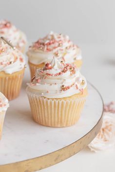 cupcakes with white frosting and sprinkles on a cake stand