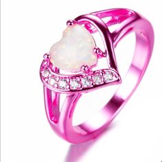 a pink ring with a heart shaped white opal and diamonds on the bottom, set in