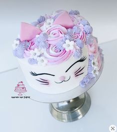 a white cake with pink and purple frosting on it's face is decorated with flowers