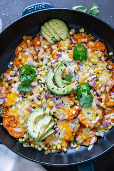 a skillet filled with corn, avocado and other toppings on top of a table