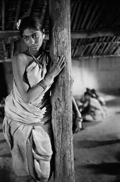 a woman standing next to a wooden pole