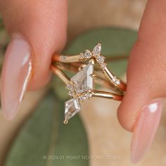 a close up of a person's hand holding a gold ring with two diamonds