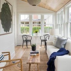 a living room filled with furniture and windows next to a wooden floor covered in white walls