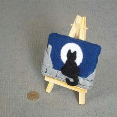 a miniature chair with a cat sitting on it next to a small dime coin holder