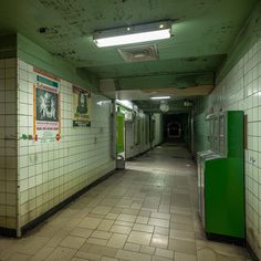 an empty subway station with urinals and posters on the walls, along with tile flooring