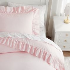 a bed with pink sheets and white pillows