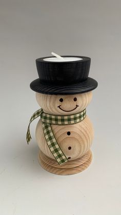 a wooden snowman with a black hat and green checkered scarf