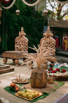 an elaborately decorated table with fruit on it and other decorations in the back ground