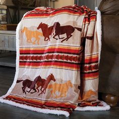 a blanket with horses on it sitting next to a brown chair in a living room