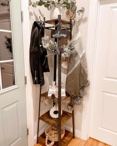 a coat rack is next to a door with a welcome sign on it and other items