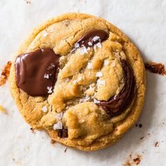 a chocolate chip cookie with sea salt and coconut on the top, sitting on a piece of parchment paper