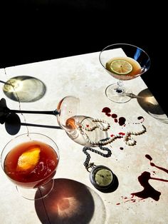 three glasses filled with drinks sitting on top of a white table next to each other