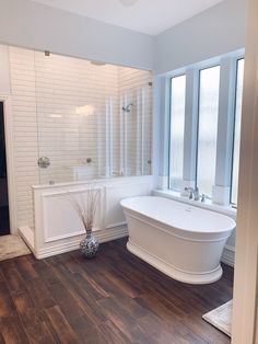 a large white bath tub sitting next to a window