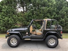 a black jeep parked in front of some trees