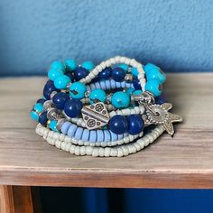 The Seven Seas bracelet is an island inspired piece that features beautiful shades of blue ( turquoise, royal blue and periwinkle) combined with silver beads and enchanting charms. Wear it with your resort outfits to elevate your look! Adjustable Blue Jewelry For Vacation, Adjustable Blue Strand Jewelry, Ocean-inspired Blue Strand Jewelry, Blue Ocean-inspired Strand Jewelry, Blue Beaded Hand-strung Bracelets For The Beach, Adjustable Blue Ocean-inspired Bracelet, Blue Wrap Bracelet For Beach, Blue Bracelet For Vacation, Handmade Blue Wrap Bracelet For Beach