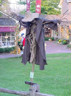 a scarecrow's hat is hanging on a post in the middle of a yard