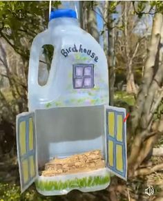 a plastic bottle shaped like a house hanging from a tree