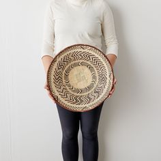 a woman is holding a woven basket in front of her face and wearing black leggings