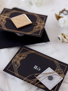 two black and gold wedding cards on top of each other