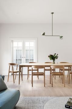 a dining table and chairs in a room with white walls, wood floors and windows