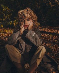 a woman sitting on the ground with her hand under her chin