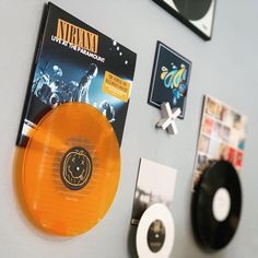 an orange disc is on the wall next to other records and cds that are hanging on the wall