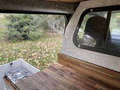 the inside of a camper with wood flooring and windows on it's side