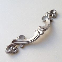 an ornate metal handle on a white surface