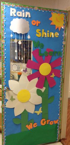 a door decorated with paper flowers and rain drops on the top, saying rain or shine we grow