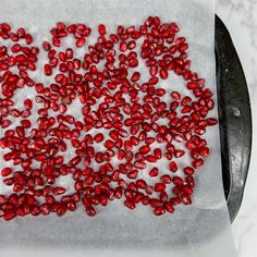 some red beads are sitting on a piece of paper next to a knife and fork