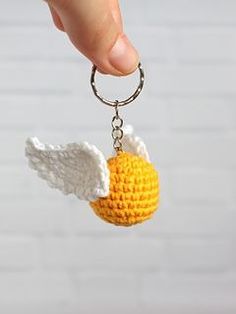 a crocheted keychain with an angel's wing and ball on it