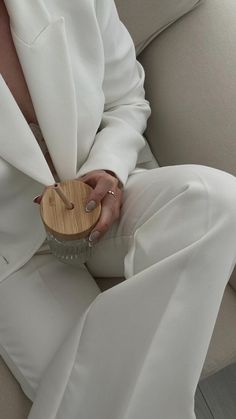 a woman sitting on a couch holding a wooden object in her hand and wearing white pants