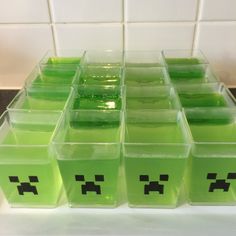 some green cubes with faces on them sitting in front of a white tile wall