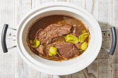 a bowl filled with meat and peppers on top of a wooden table