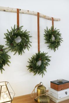 three christmas wreaths hanging on a wall next to a lamp and other items in front of it