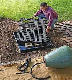 a man kneeling down next to a hole in the ground with a hose attached to it