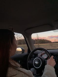 a woman sitting in the driver's seat of a car looking out the window