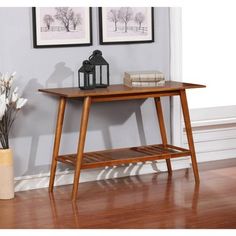 a wooden table sitting on top of a hard wood floor next to a vase with flowers