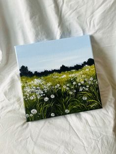 a painting of white flowers in a green field on a white sheet with trees in the background