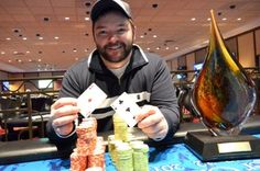 a man sitting at a table with stacks of poker chips in front of him holding cards