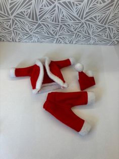 two red and white santa hats laying on top of a bed