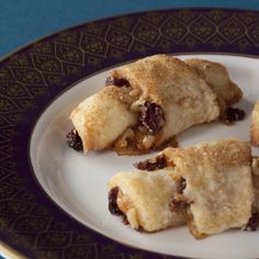 three pastries on a plate sitting on a blue tablecloth with gold trimmings