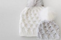 two white knitted hats with grey pom - poms