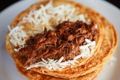 three tortillas topped with shredded cheese and meat