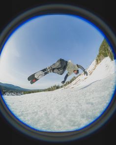 a man flying through the air while riding a snowboard on top of a snow covered slope