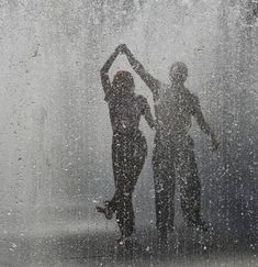 two people standing in the rain with their hands up