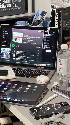 an open laptop computer sitting on top of a desk next to a cell phone and other electronics