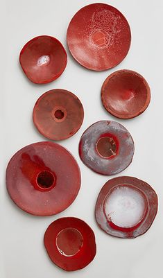 several red and white plates sitting on top of each other in front of a white background