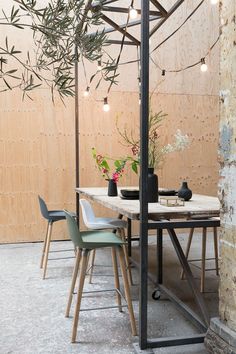 an outdoor dining area with table, chairs and potted plants on the side wall