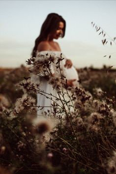 a pregnant woman standing in a field of flowers